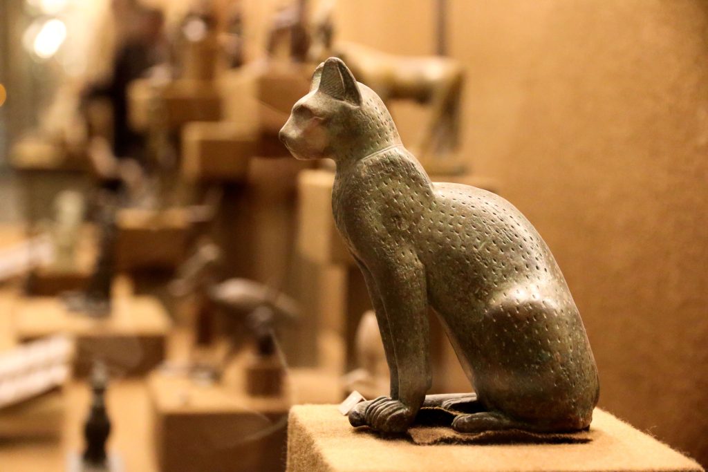 Bronzefarbene Katzenstatue nach altägyptischem Vorbild in einer Ausstellung.